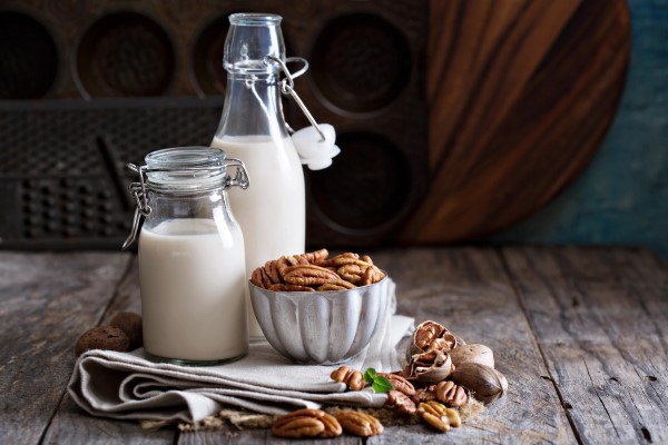 Bowl of Pecans Sitting next to Decanter of Nut Milk