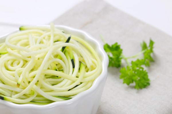 Bowl of zucchini noodles with a parsley garnish to the side