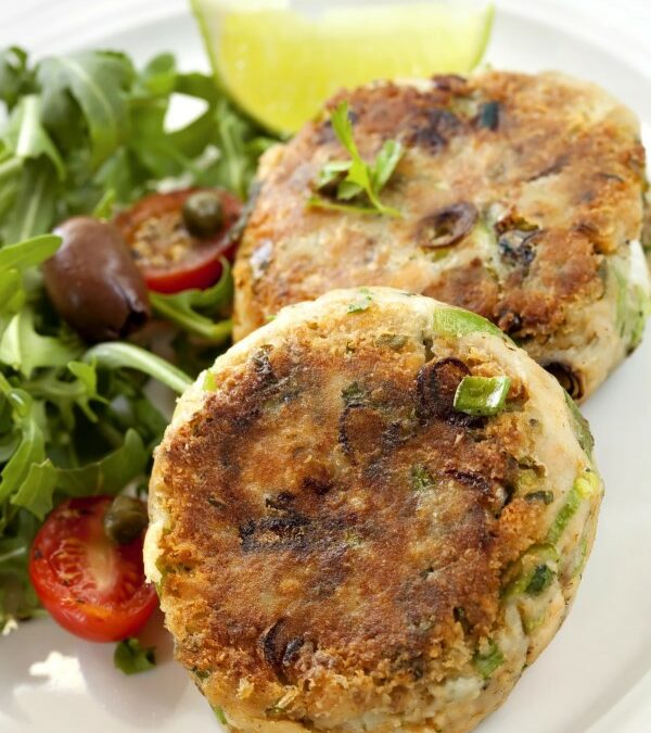 Two salmon patties with a side arugula salad and a lime wedge