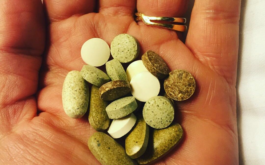 Hand holding a pile of herbal-based vitamins
