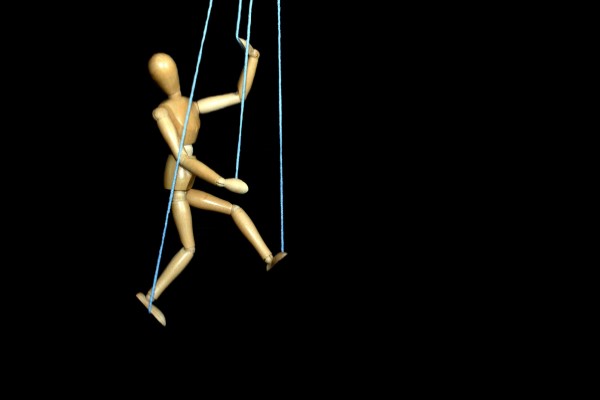 Wooden art model hanging in motion by puppet strings