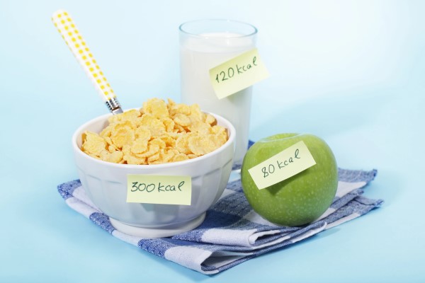 Bowl of cereal, glass of milk, and an apple, all with sticky notes noting how many calories are in them